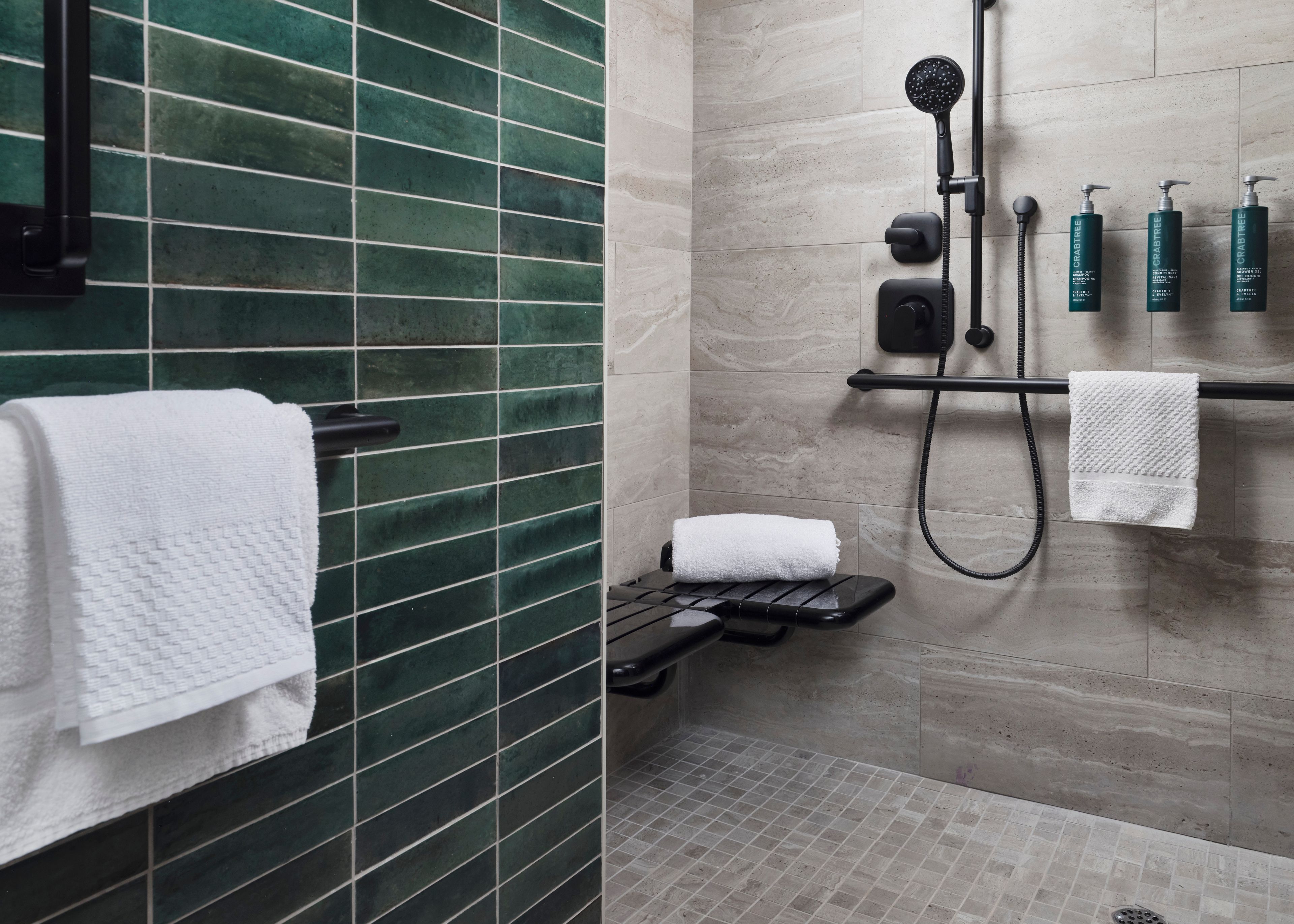 A modern bathroom with a shower, a towel rack, and a shelf with toiletries.