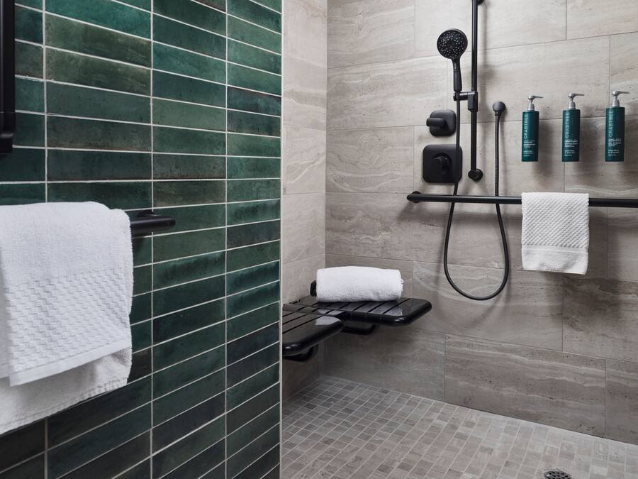 A modern bathroom with a shower, a towel rack, and a shelf with toiletries.