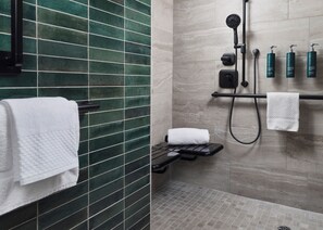 A modern bathroom with a shower, a towel rack, and a shelf with toiletries. - Hilton Stockton (Stockton)