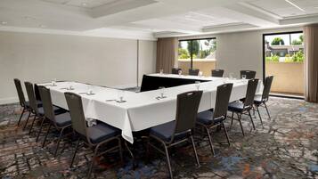 A conference room with a long table, chairs, and a view of buildings through a large window.