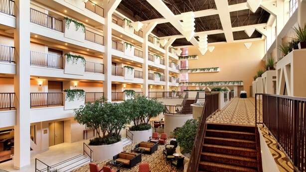 En hotellobby med flera våningsplan, försedd med balkonger, sittgrupper och trappor.