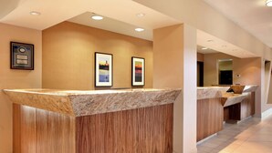 A reception desk with a wooden finish and a marble top, flanked by two framed pictures on the wall.