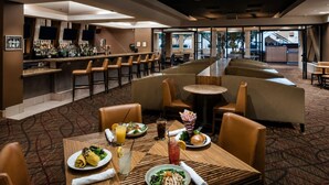 A restaurant with a bar area, seating arrangements, and a view of the outdoors.
