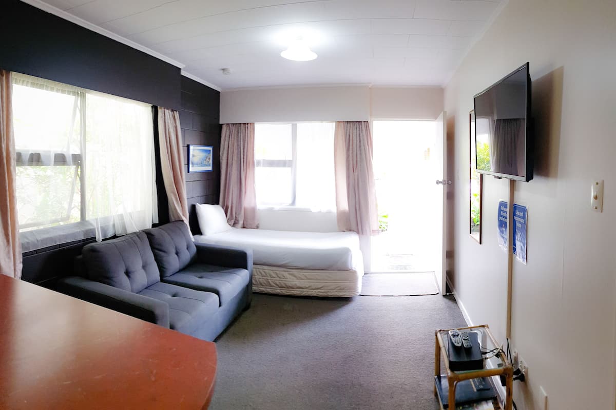 Ein Zimmer mit einem Bett, einer Couch, einem Fernseher und einem Tisch.