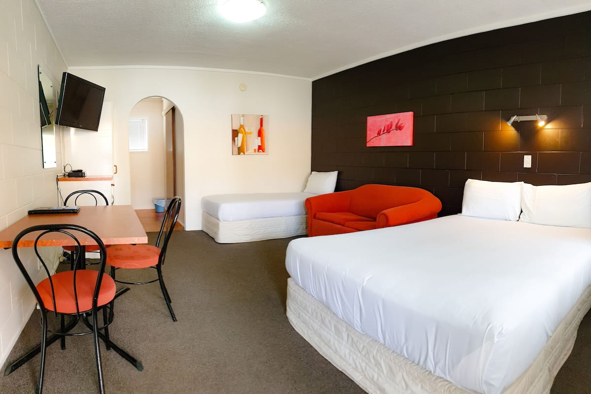 Ein Hotelzimmer mit einem großen Bett, einem Schreibtisch mit Stühlen, einem Fernseher und Bildern an den Wänden.