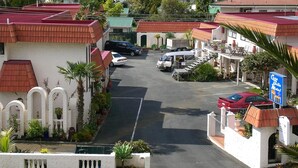 A motel with a parking lot, a view of the sea, and a mountainous landscape in the background. - Casa Bella Motel (Paihia)