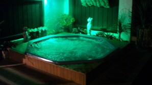 A hot tub with a wooden deck and a small waterfall feature, surrounded by potted plants and a wooden fence. - Casa Bella Motel (Paihia)
