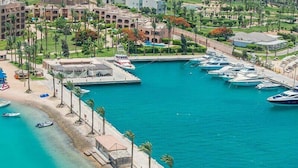 A marina with boats docked, a beach with palm trees, and a resort with multiple buildings. - Continental Hotel Hurghada (Hurghada)