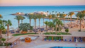 A resort with a pool, beach umbrellas, and palm trees. - Continental Hotel Hurghada (Hurghada)