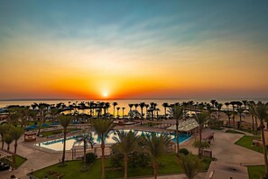 A resort with a pool, palm trees, and a sunset view.