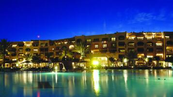 Et stort hotel med flere balkoner og en swimmingpool om natten.