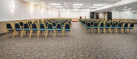 A conference room with rows of chairs, a podium, and an American flag.