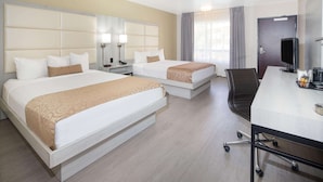 Hotellihuone, jossa on kaksi sänkyä, työpöytä tietokoneella ja televisio.