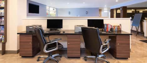 A modern office space with two desks, chairs, a flat-screen TV, and a bookshelf.