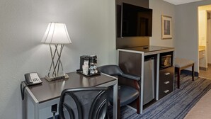 A hotel room with a desk, a lamp, a coffee maker, a chair, a television, and a microwave. - Best Western Plus Reading Inn & Suites (Shillington)