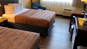 A hotel room with two beds, a desk, a chair, and a TV.