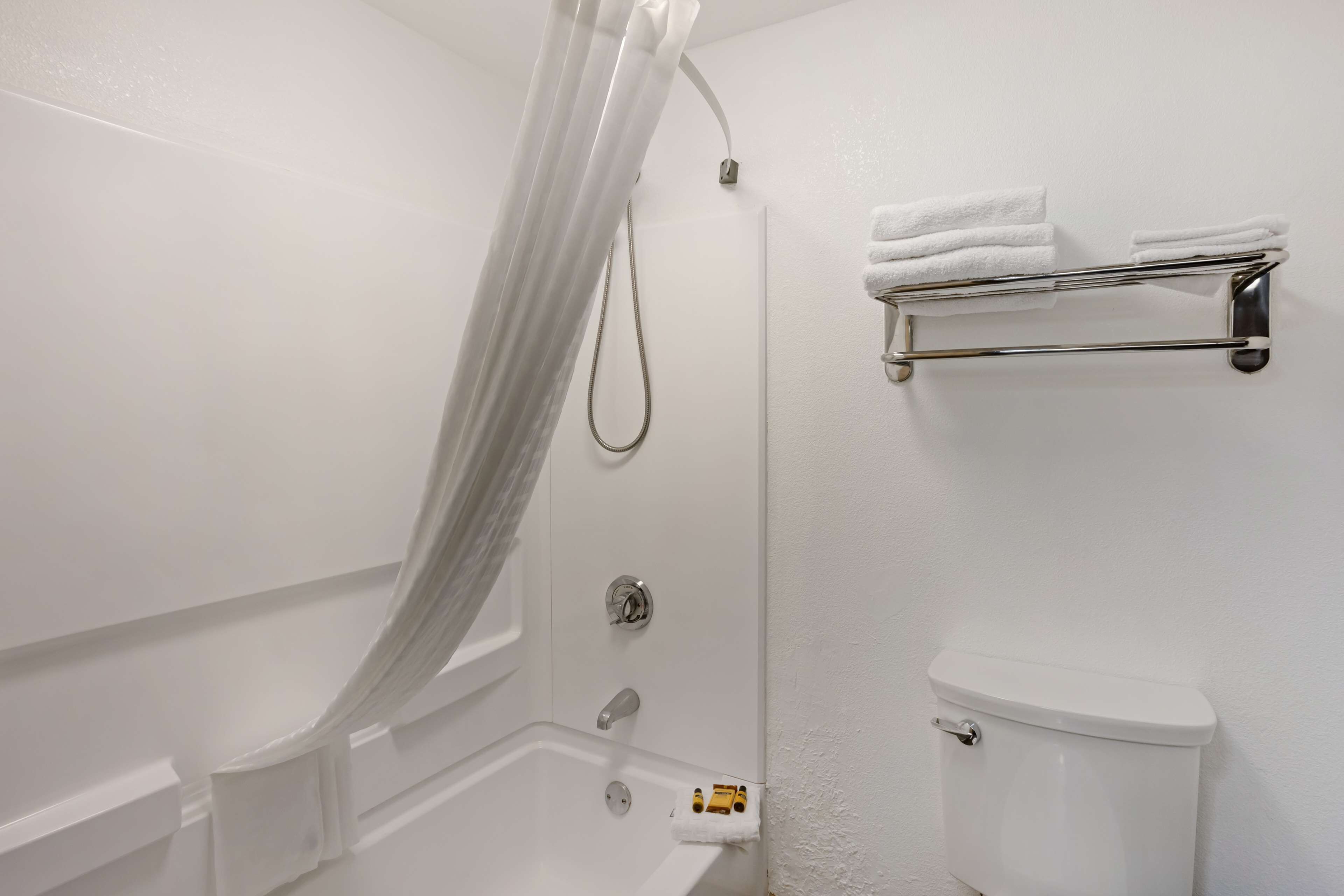 Un baño con ducha, inodoro y tendedero para toallas.