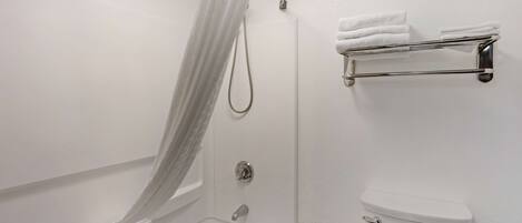 Un baño con ducha, inodoro y tendedero para toallas.