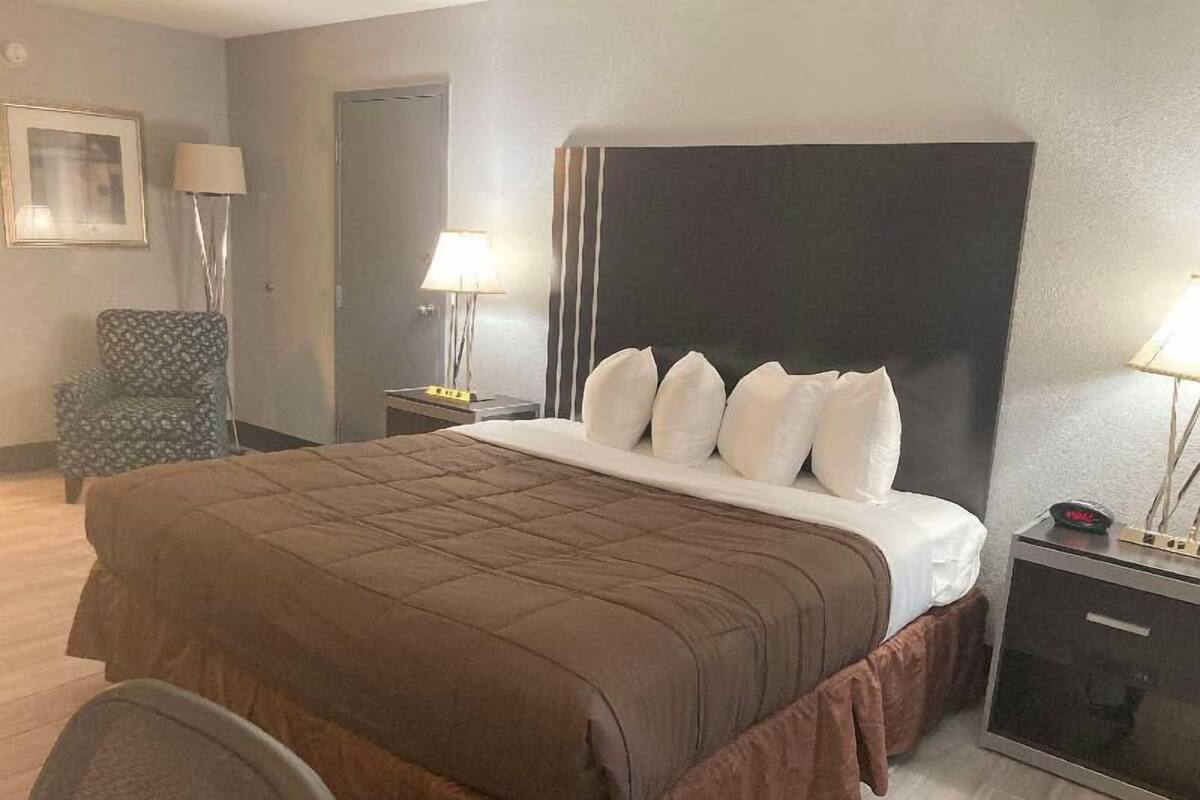 A hotel room with a large bed, two bedside tables, a chair, and a door.