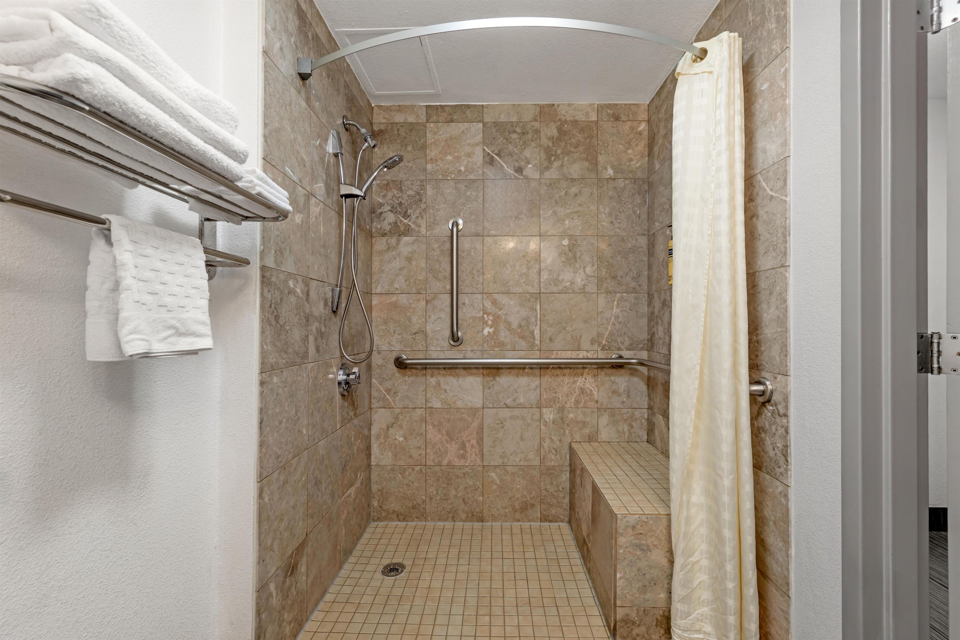 A walk-in shower with a handrail, a towel rack, and a shower curtain.