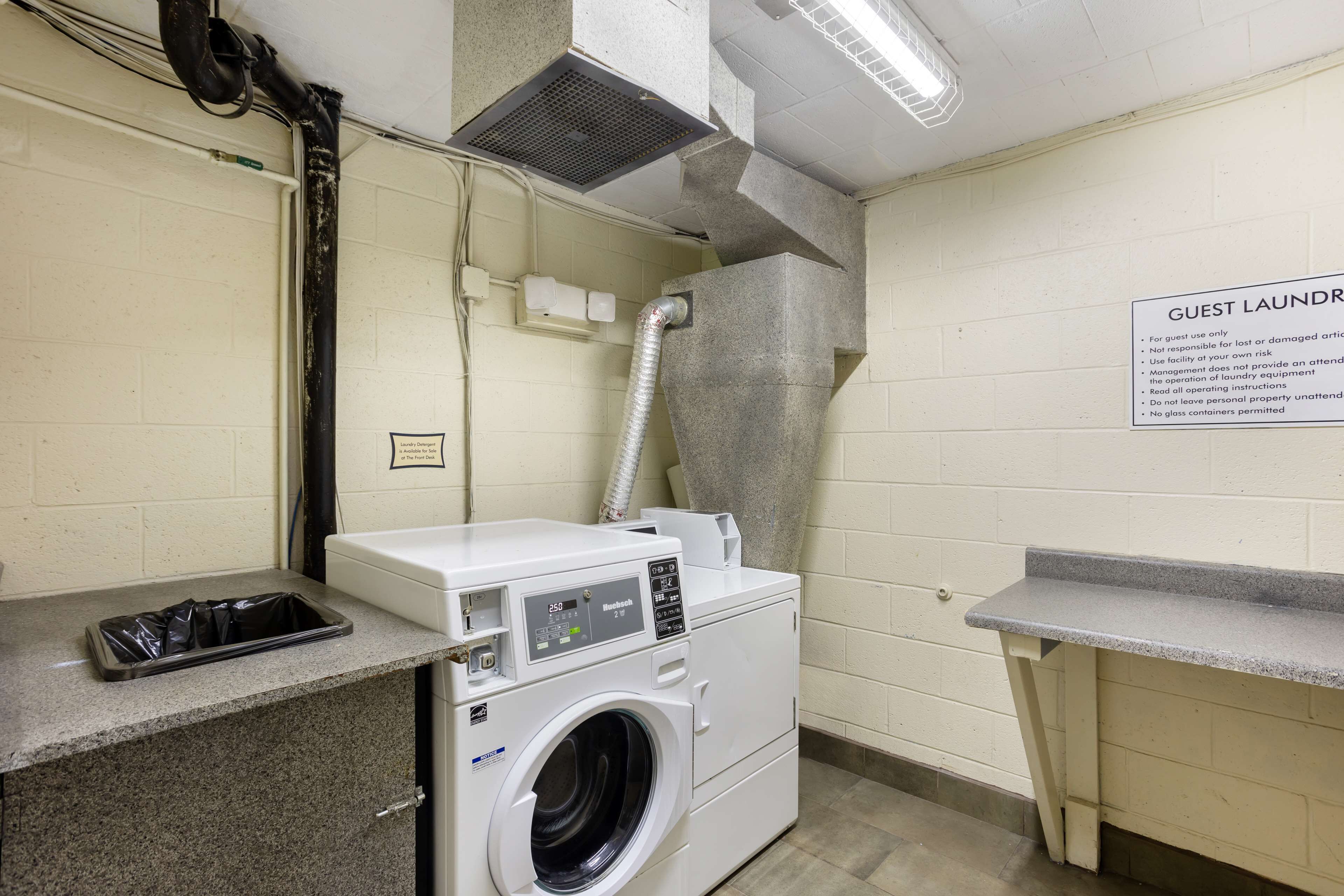 A guest laundry area with a washing machine, dryer, and a sign detailing usage instructions.