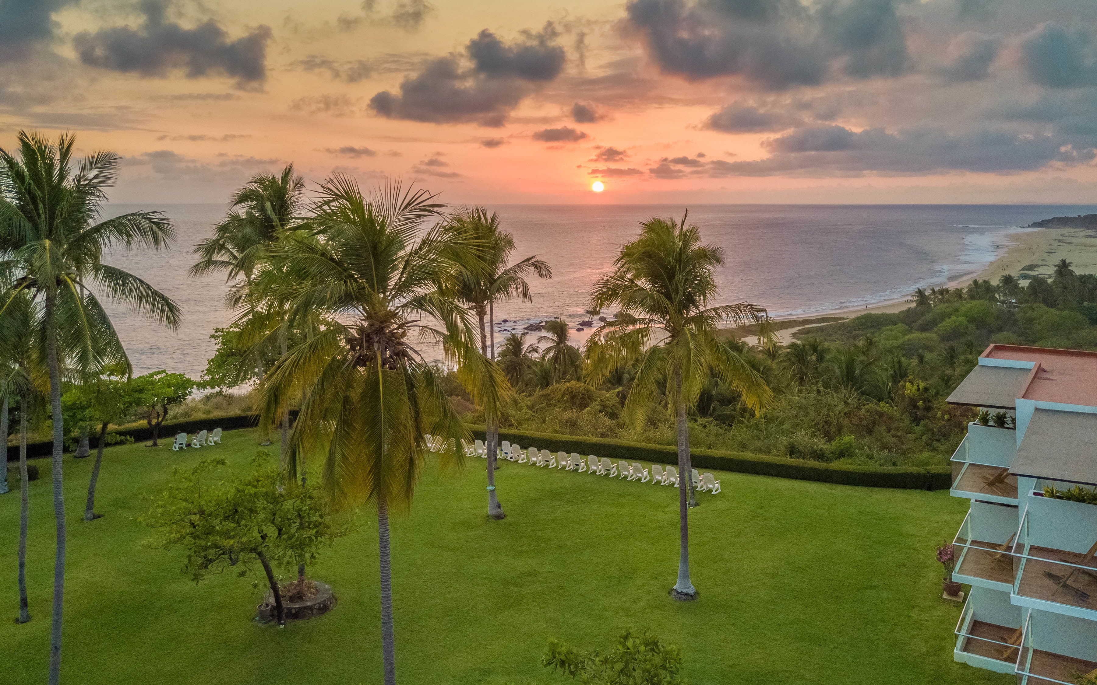 A tropical resort with a view of the ocean and palm trees.