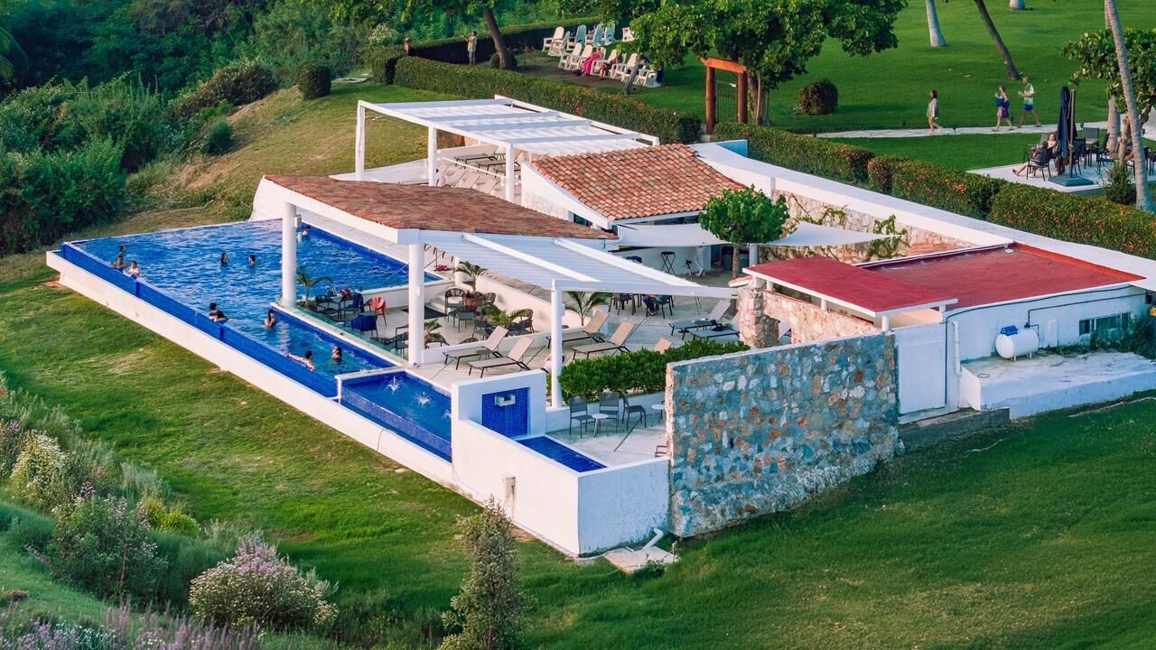 Un complejo turístico con piscina, mobiliario exterior y una pared de piedra.