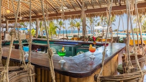 A bar area with a thatched roof, wooden bar counter, and hanging ropes. - Posada Real Puerto Escondido (Puerto Escondido)