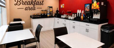 A breakfast area with a counter, coffee machines, and seating.