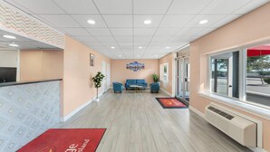 A reception area with a counter, seating area, and a view of the outdoors through large windows. - Econo Lodge Cranston - Providence (Cranston)