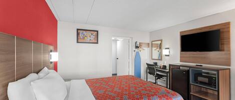 A hotel room with a bed, a desk, a microwave, and a TV.