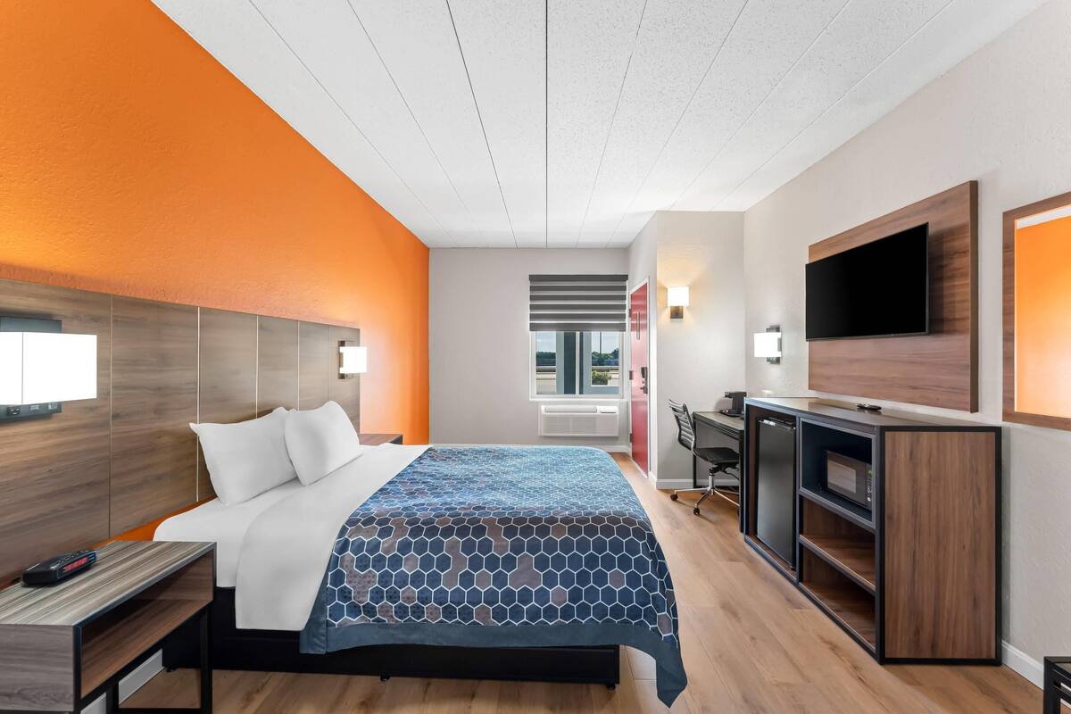 Una habitación de hotel moderna con una cama, un escritorio, una televisión y vistas al exterior.