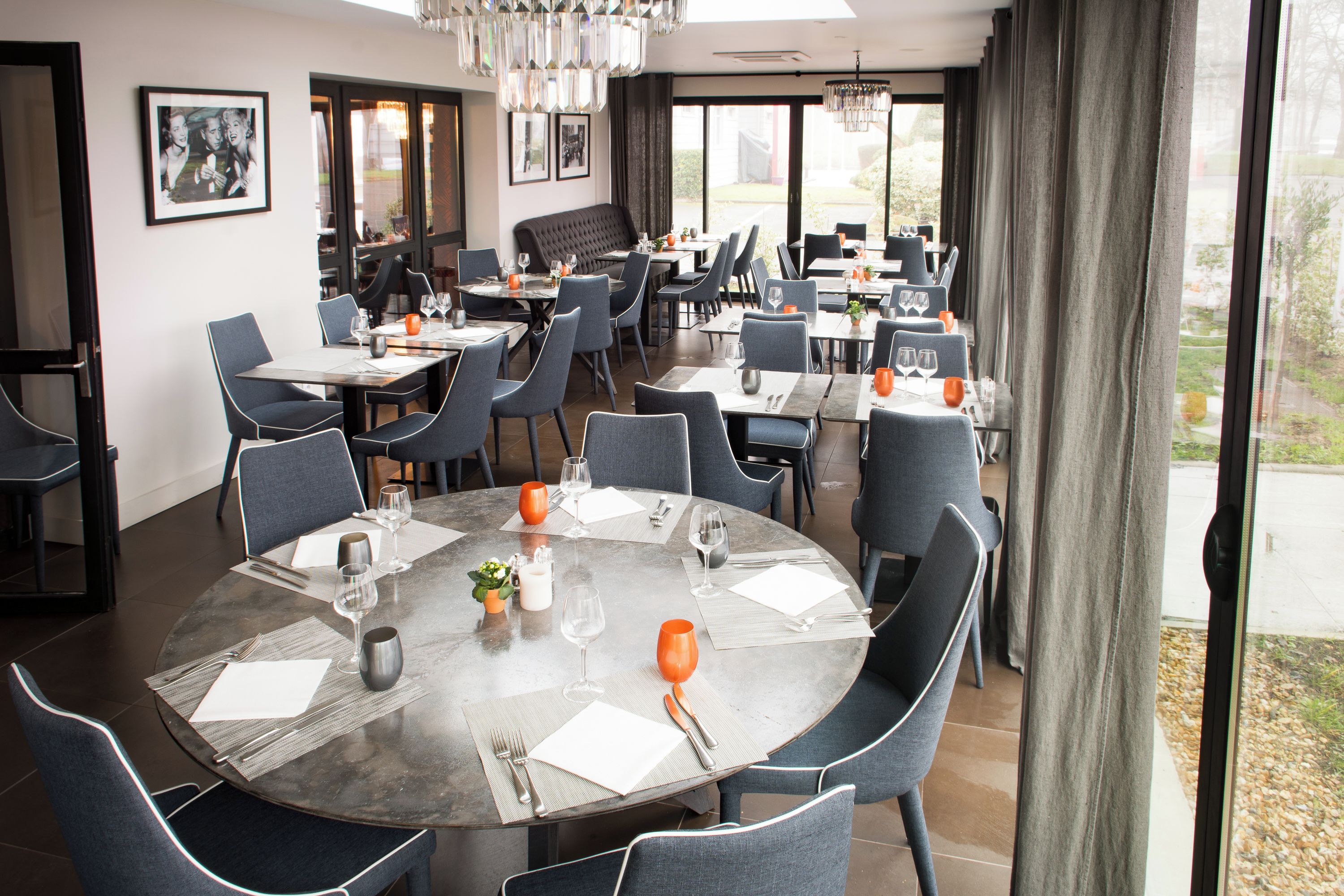Un restaurant avec des tables et des chaises rondes, et une vue sur l’extérieur.