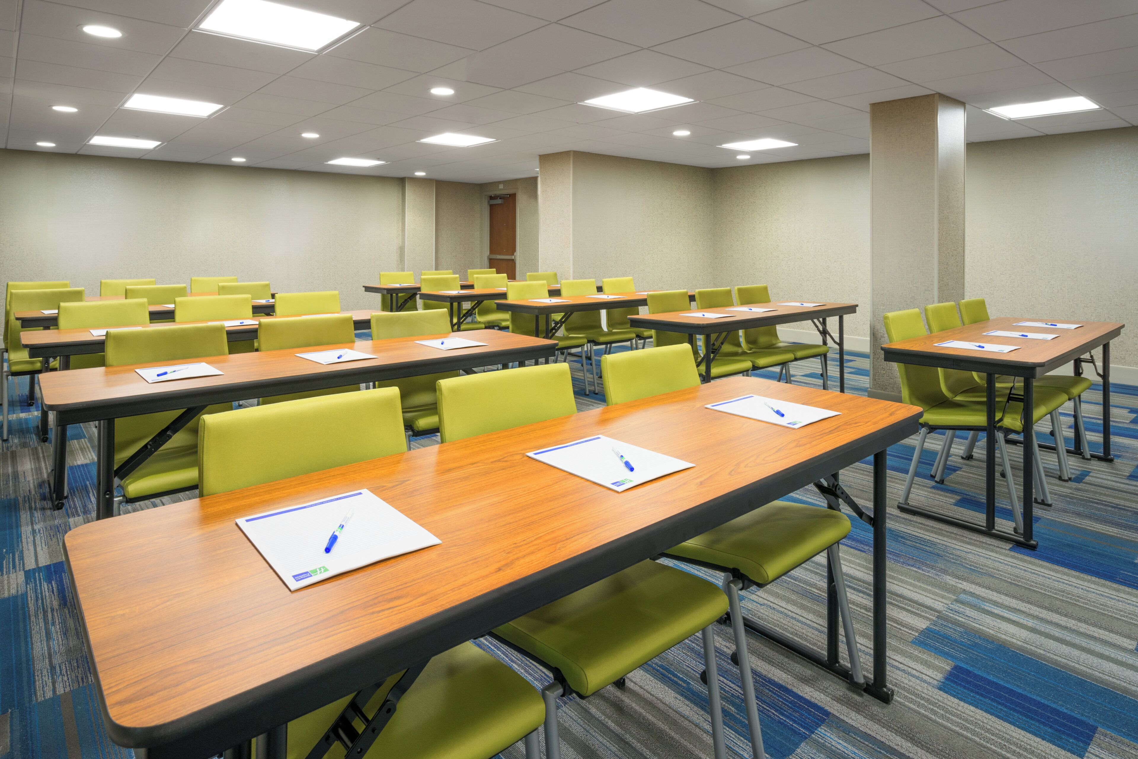 Un salón de conferencias con varias mesas y sillas, equipado con tarjetas de identificación y bolígrafos.