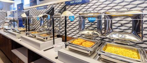 Zona de bufé con diversas opciones de comida, incluyendo platos calientes y una sección llamada 'EGG-XACTLY'.
