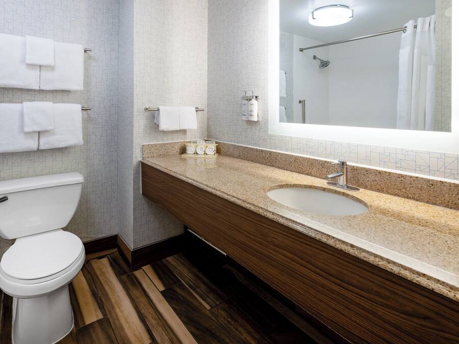 A modern bathroom with a toilet, sink, and mirror.