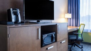 Habitación de hotel con televisión de pantalla plana, cafetera, microondas y escritorio con silla.