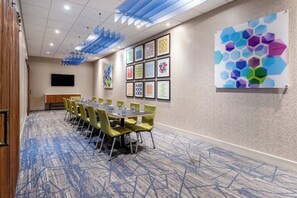 A conference room with a long table, yellow chairs, and a blue carpet.