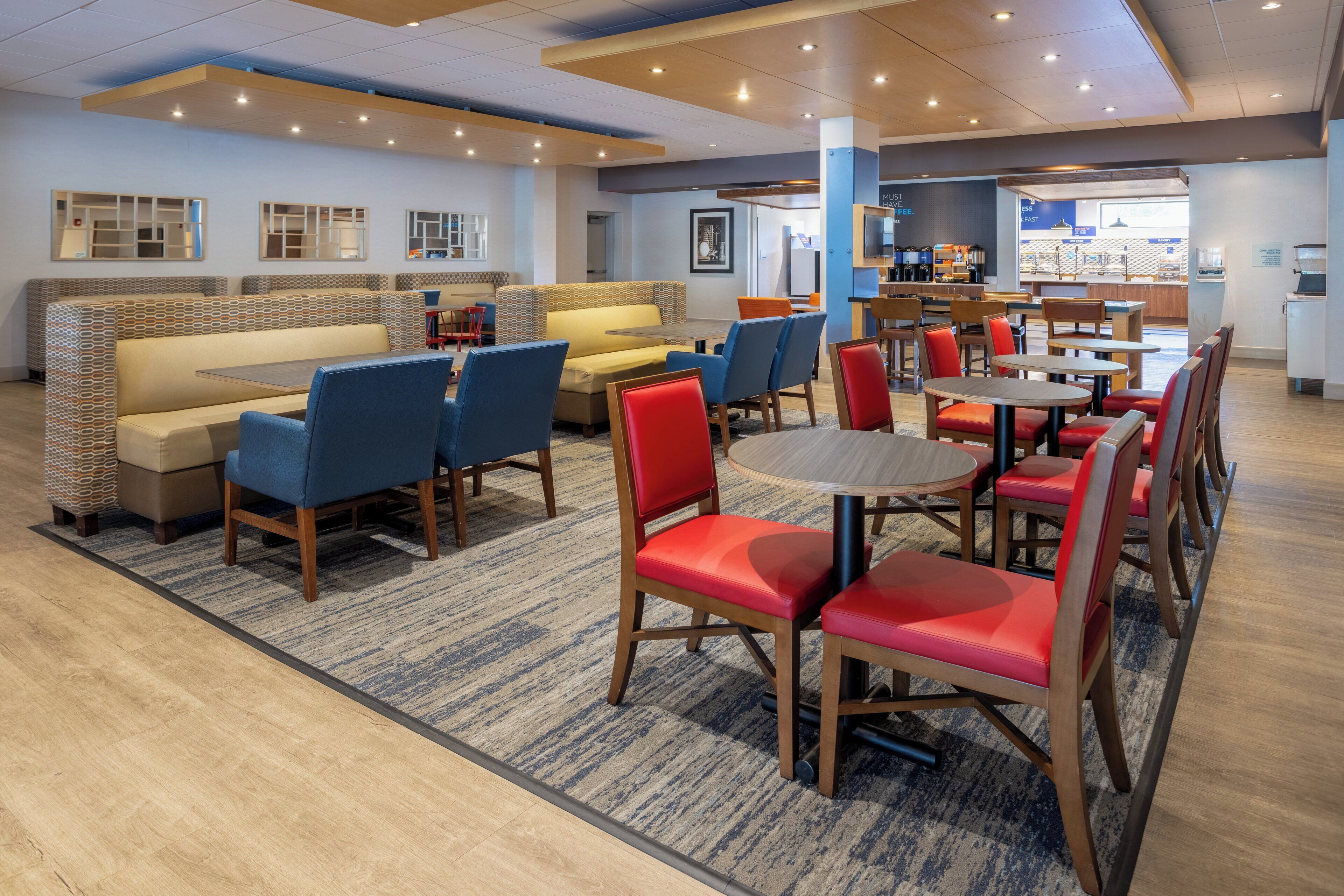 A hotel lobby with seating areas, a coffee bar, and a counter with a menu.