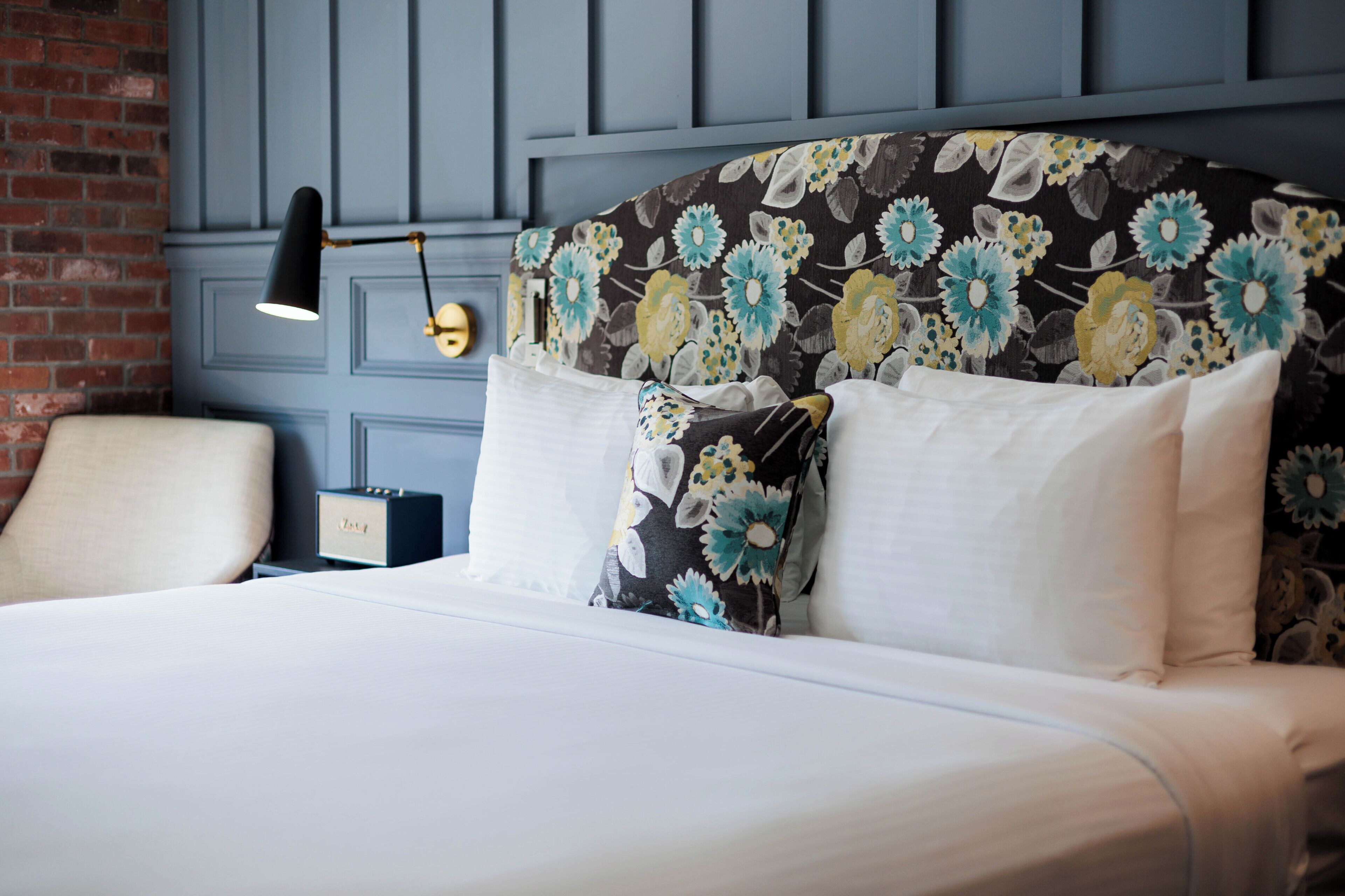 A bed with a floral headboard, a bedside lamp, and a nightstand with a radio.