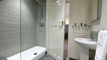 Un baño moderno con cabina de ducha de vidrio, un lavamanos blanco y un perchero para toallas.