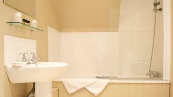 A bathroom with a sink, mirror, and shower.