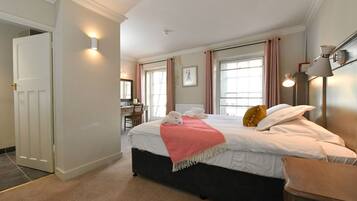 A hotel room with a bed, bedside table, lamp, and a desk with a chair.