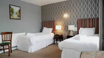 Habitación de hotel con dos camas, una silla, una lámpara y un cuadro en la pared.