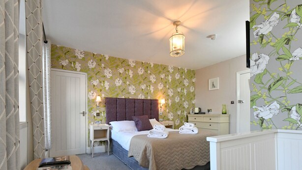 A bedroom with a bed, bedside tables, a nightstand, a lamp, a dresser, and a small table with a magazine.
