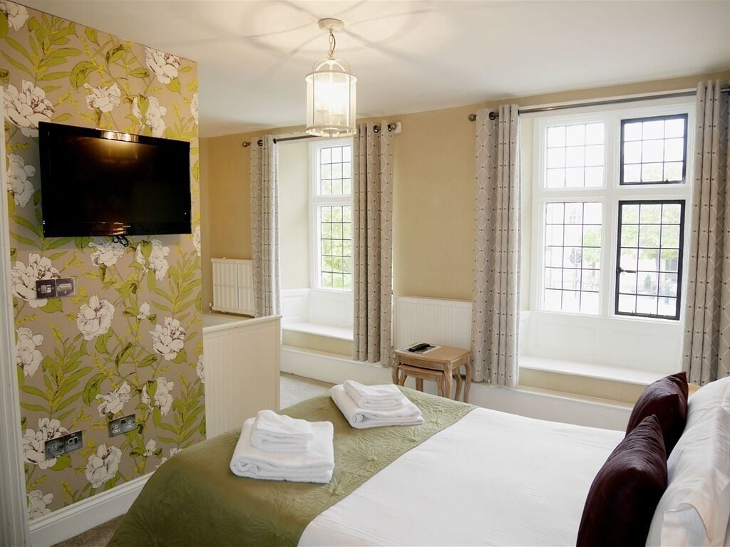 Een hotelkamer met een bed, een televisie, een raam met gordijnen en een tafeltje.