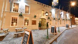 A historic hotel with a classic facade, outdoor seating, and a prominent sign.