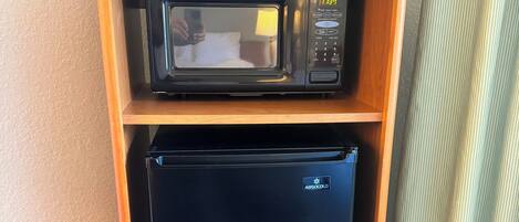 Uma cozinha compacta com micro-ondas e mini-geladeira.