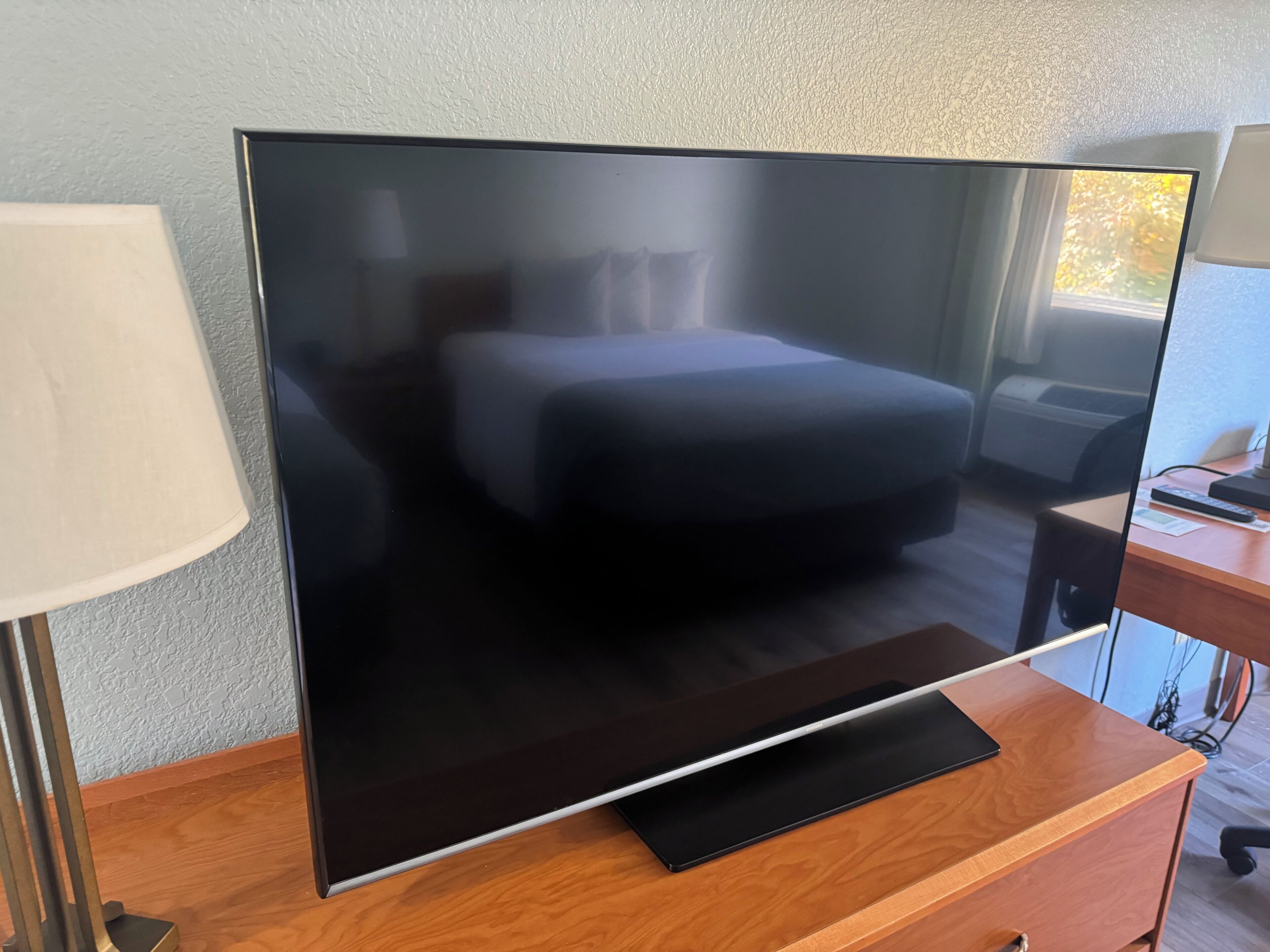 A large flat-screen TV on a wooden TV stand in a hotel room.