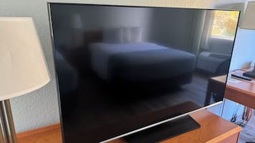 A large flat-screen TV on a wooden TV stand in a hotel room.